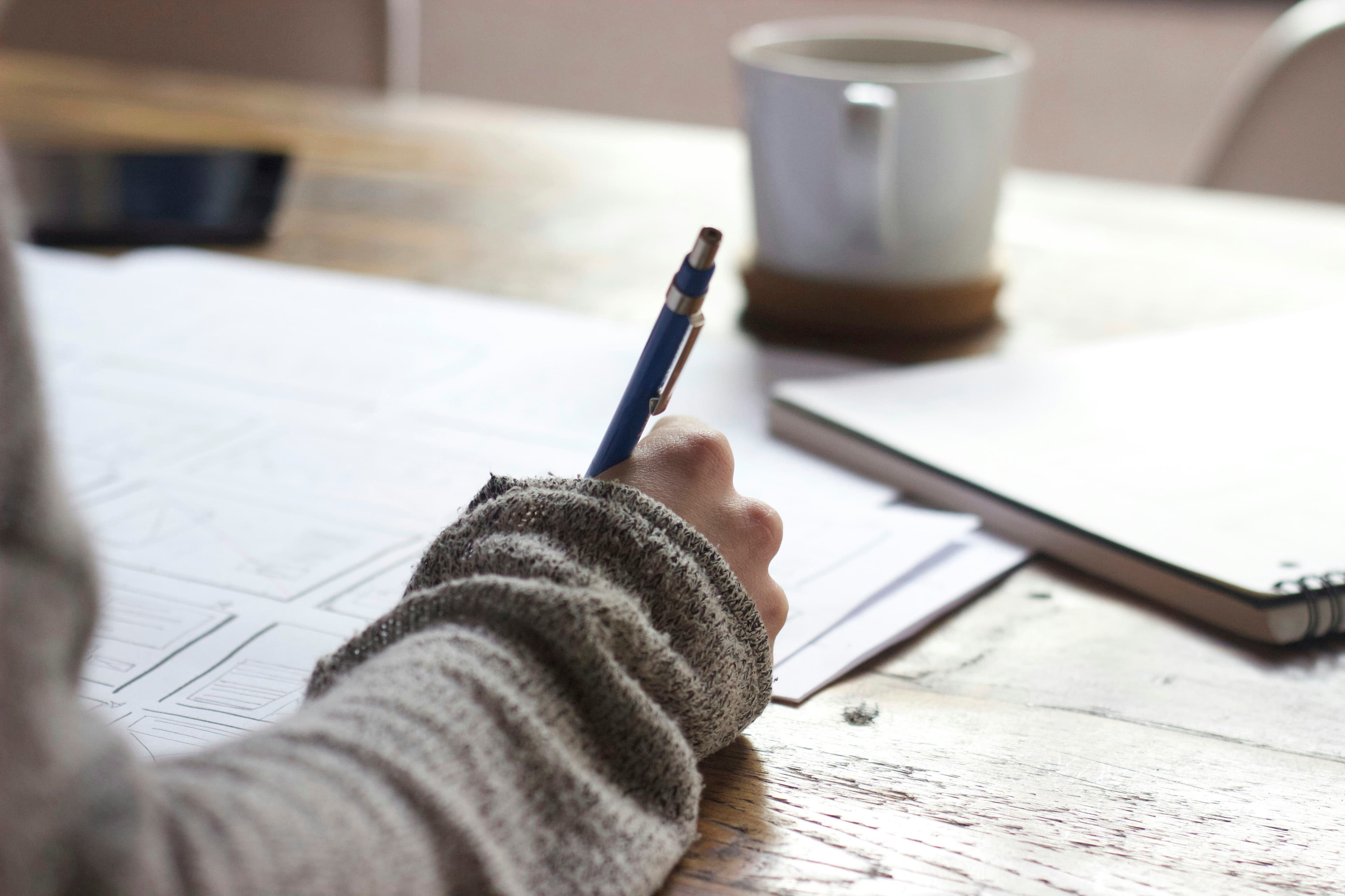 Person writing structured documentation at a desk, representing how to write an effective CLAUDE.md file